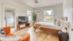 A modern bedroom with a bed, a TV, a plant, and a view of the outside.