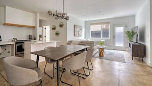Eine moderne Küche mit Essbereich, ein Wohnzimmer mit Sofa und Fernseher.