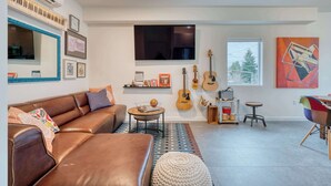 A modern living room with a brown leather sofa, a coffee table, and a large window. - Luxury Penthouse - Rooftop Deck - 3BR - AC (Portland)