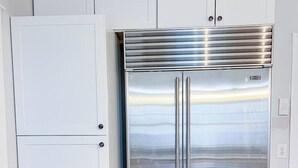 A kitchen with a stainless steel refrigerator and a white double-door refrigerator.