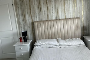 A bedroom with a bed, two bedside tables, a lamp, and a nightstand.