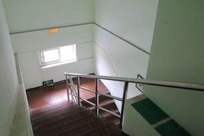 A staircase with a metal handrail, a small window, and a green mat at the bottom. - Jiangyang Business Hotel (Shanghai Shuangyang Road) (Shanghai)