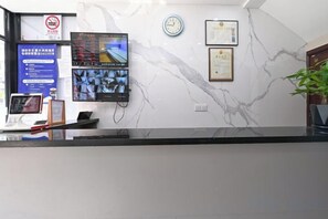 A hotel reception area with a marble wall, a clock, and a digital display. - Jiangyang Business Hotel (Shanghai Shuangyang Road) (Shanghai)