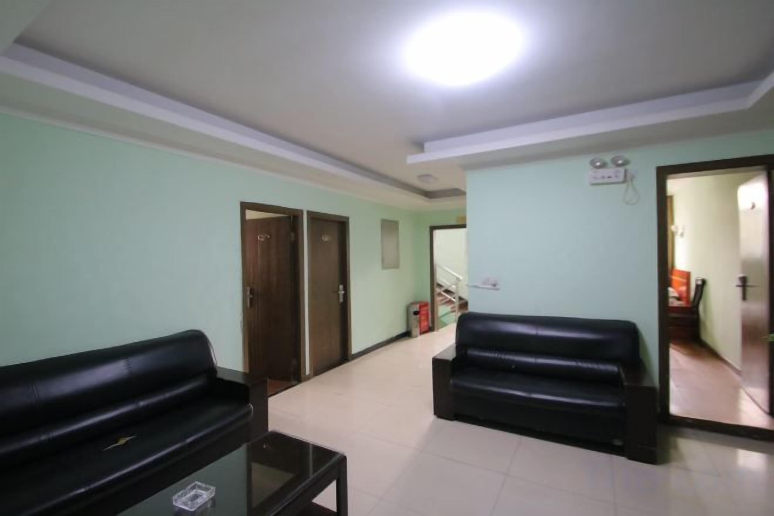 A living room with two black sofas, a coffee table, and a door leading to another room.