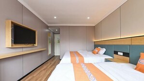 Una camera d'albergo con due letti, una TV fissata al muro e pavimento in legno.