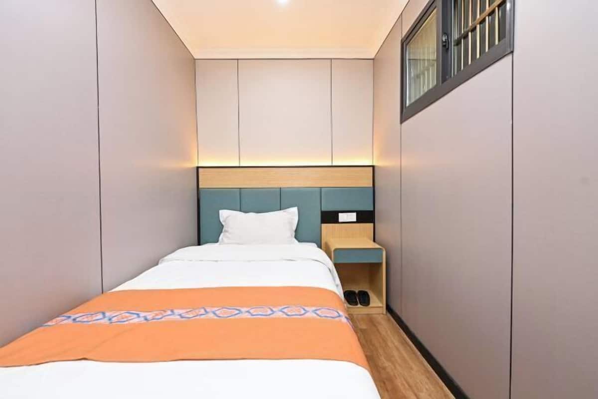 A hotel room with a bed, a bedside table, a nightstand, and a window.