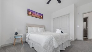 Ein Schlafzimmer mit einem Bett, einem Nachttisch, einem Bild des Eiffelturms und einem Kleiderschrank.