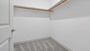 Ein Eckschrank mit weißen Wänden, Holzbalkendecke und einem grauen Streifen Teppich.
