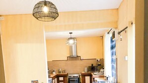 A modern kitchen with a dining area, featuring a wooden table and chairs, a built-in oven, and a white refrigerator. - Charming villa in Pereybère and walking distance to the beach with private pool. (Grand Baie)