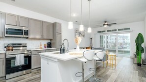 A modern kitchen with stainless steel appliances, a large island with bar stools, and a dining area with a view. - Refined Comforts: Luxe Stay in Whitestown Indiana (Perry Township)