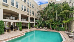 A pool area with a curved edge, surrounded by lounge chairs and potted plants. - Perfect Palm Beach Location #2, spacious Condo, WiFi, AC in fabulous Palm Beach. (Palm Beach)