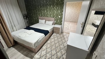 Een hotelkamer met een bed, nachtkastjes, een kledingkast, een spiegel en een kamerbreed tapijt.