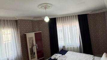 Una habitación de hotel con cama, armario, escritorio y una alfombra estampada.