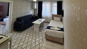 A modern hotel room with a sofa, a bed, a small table, and a ceiling light. - Ist Suit Otel (Van)