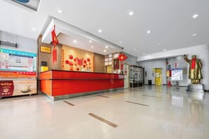 A hotel reception area with a red counter, a statue, and a clean, modern interior. - 7 Days Inn (Zibo Zhou Village Gushangcheng Street) (Zibo)