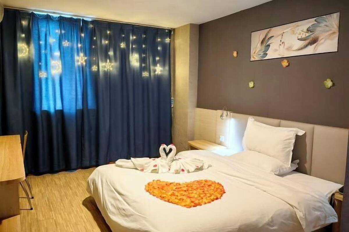 A hotel room with a bed, a desk, and a window with curtains.