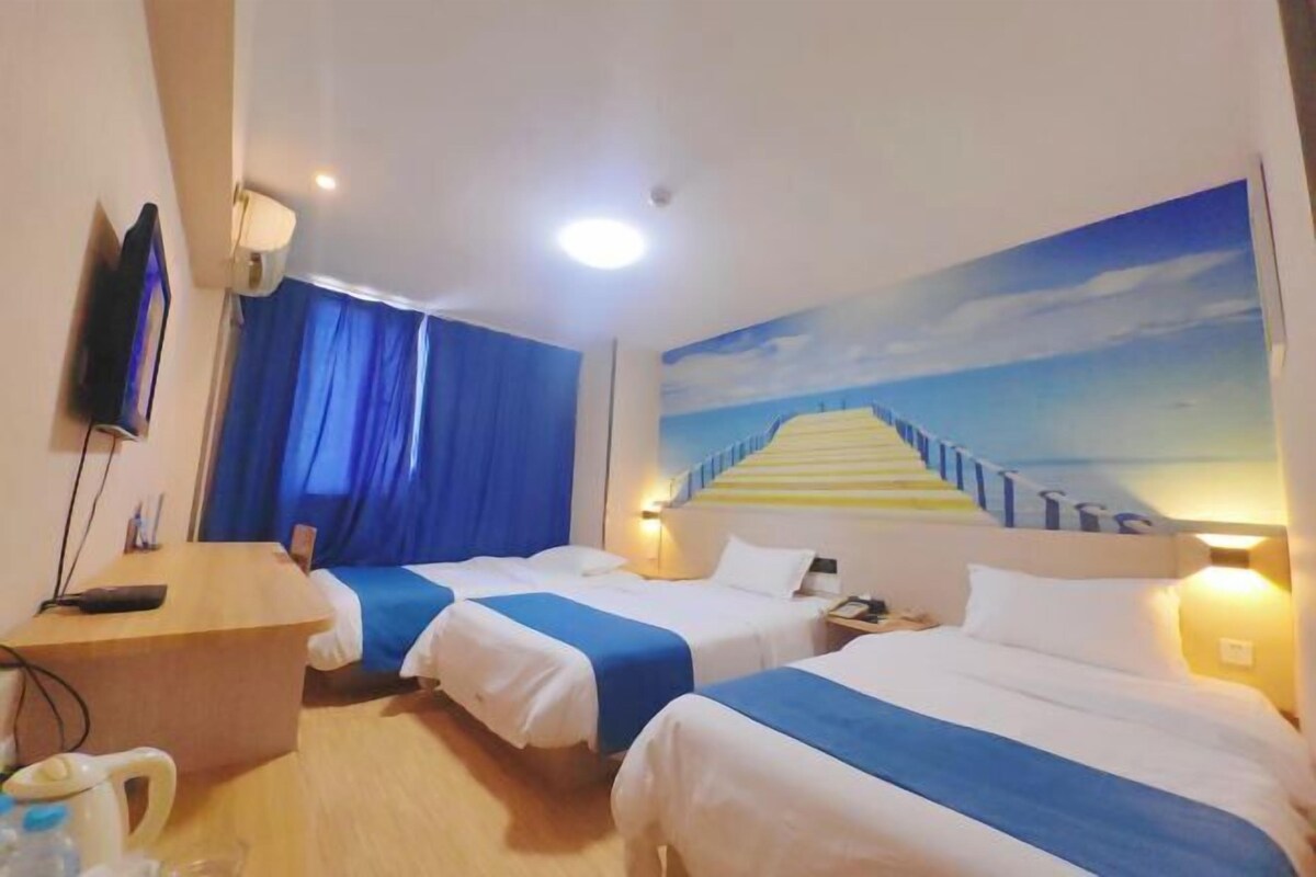 Habitación de hotel con dos camas, un escritorio, un televisor y un cuadro de una escalera.