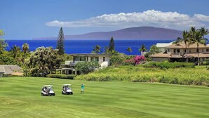 Ein Golfplatz mit Blick auf das Meer und einem Berg im Hintergrund.