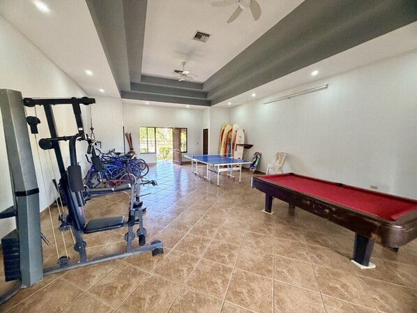 A gym with exercise equipment, a ping pong table, and a pool table.