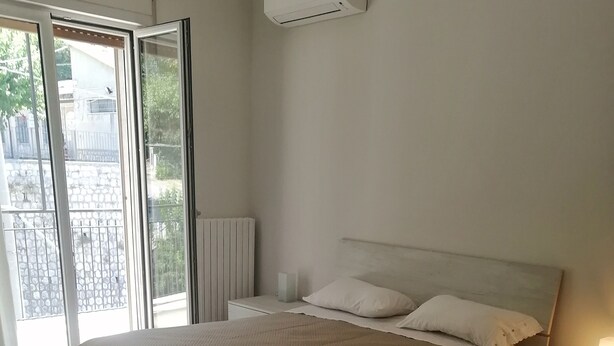 Ein Schlafzimmer mit Bett, Nachttisch, Lampe und Heizkörper.