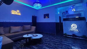 Una stanza con un divano, due tavolini, un lampadario e insegne luminose per Donho Luxury Apartments.