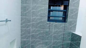 Une petite salle de bain moderne, équipée de toilettes, d’une douche et d’une petite fenêtre.