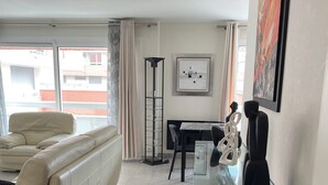 Una sala de estar moderna con un sofá, una mesa de centro de vidrio, una mesa de comedor con sillas y una lámpara de pie.