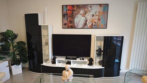 Una sala de estar moderna con una mesa de centro de vidrio curvo, un televisor de pantalla plana y una decoración minimalista.