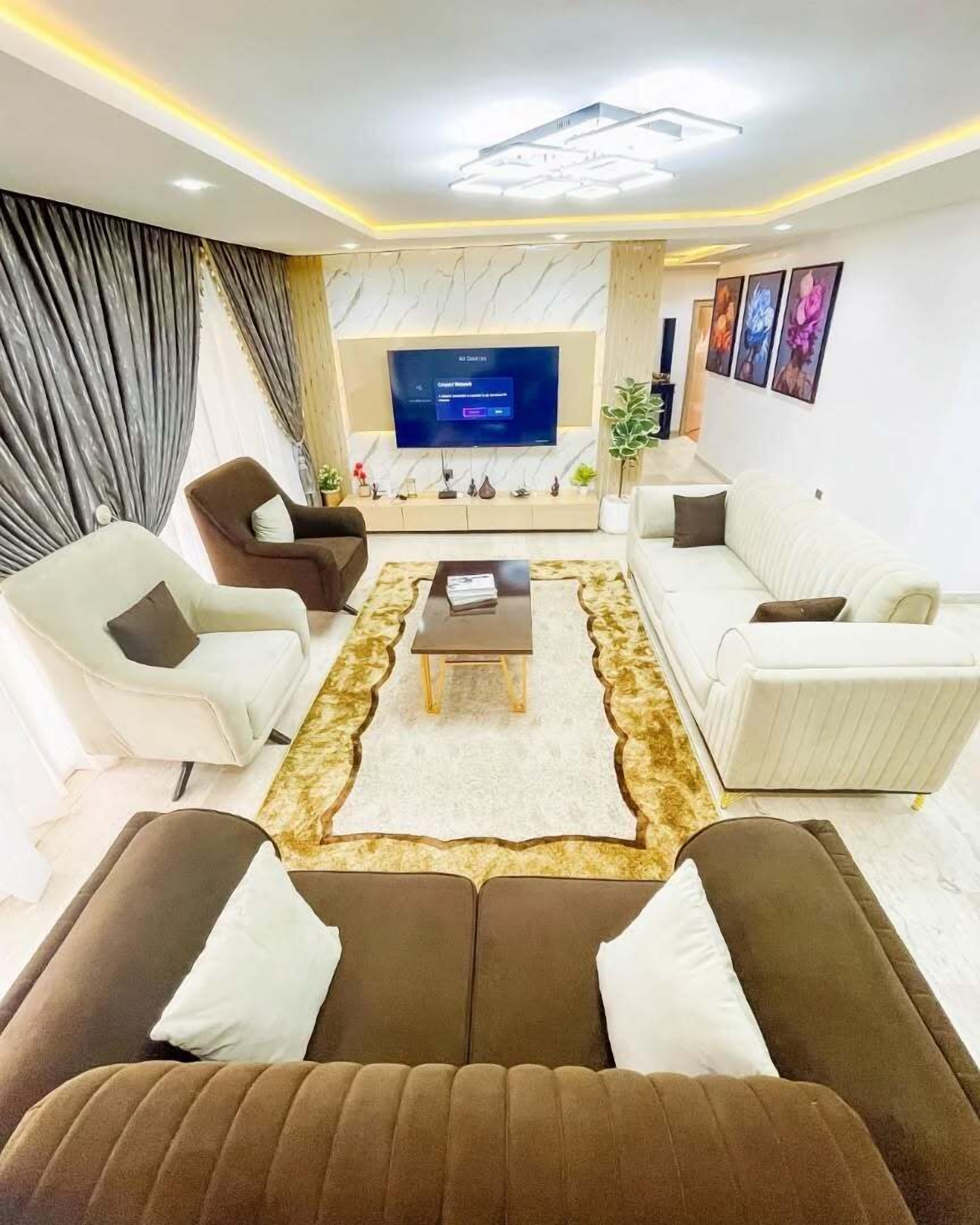 A modern living room with a flat-screen TV, two sofas, a coffee table, and a patterned rug.