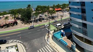 A modern building with a curved facade, a pool area, and a view of the ocean and beach.