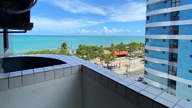 A balcony with a view of the ocean and a building.