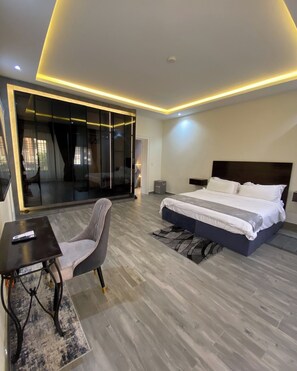 A modern bedroom with a large bed, a desk, and a chair.