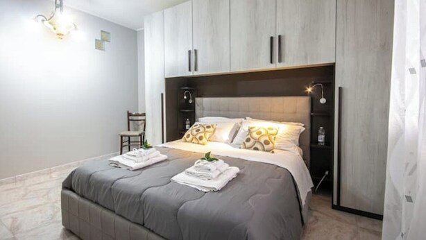 Ein modernes Schlafzimmer mit einem großen Bett, integriertem Kleiderschrank und einer Kronleuchter.
