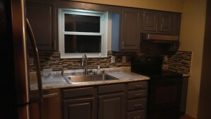 A kitchen with dark cabinets, a stainless steel refrigerator, a microwave, and a window above the sink. - 10acre Serene Retreat W/ ⭐️⭐️⭐️⭐️⭐️Private Chef Availability!!  (Mars)