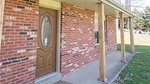 A two-story house with a brick facade, a front porch with wooden posts, and a single door. - 10acre Serene Retreat W/ ⭐️⭐️⭐️⭐️⭐️Private Chef Availability!!  (Mars)