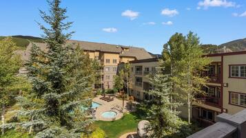 A multi-story building with a courtyard featuring a swimming pool, outdoor seating, and a well-maintained lawn.