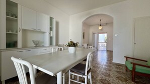 Une cuisine spacieuse avec des meubles blancs et un coin repas comprenant une longue table et des chaises.
