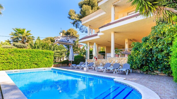 A swimming pool with lounge chairs and umbrellas, surrounded by greenery and a building with a balcony. - Private Pool & Stunning Mountain Views (Tarragona)