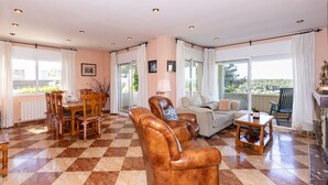 A spacious living room with a checkered floor, a dining area with a table and chairs, a sofa, and a small table with a lamp. - Private Pool & Stunning Mountain Views (Tarragona)