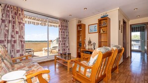 A spacious living room with a large window, wooden furniture, and a bookshelf. - Private Pool & Stunning Mountain Views (Tarragona)