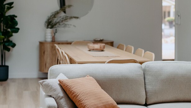 A modern living room with a sofa, a dining table, and chairs.