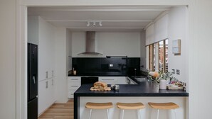 A modern kitchen with white cabinets, a black countertop, and a central island with stools.