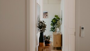 A hallway with a wooden floor, a white door, and a small wooden table with a potted plant.