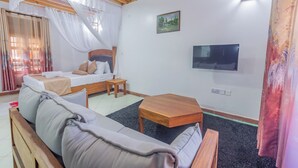 Ein Zimmer mit einem Bett, einem Schlafsofa, einem kleinen Tisch, einem Fernseher und einem Bild an der Wand.