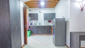 Eine Küche mit dunklen Holzschränken, einem Kühlschrank und einer Mikrowelle.