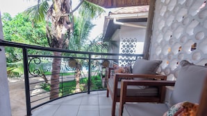 Ein Balkon mit Metallgeländer, einer Holzsofa und einer Wand mit Muster.
