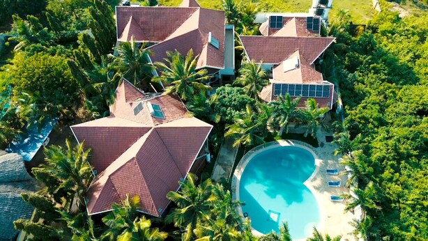 Ein Luftbild eines Resorts mit mehreren Gebäuden, einem Schwimmbad und üppiger Bepflanzung.