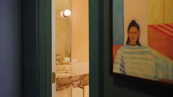 Une salle de bain avec un lavabo en marbre, un miroir et un tableau encadré au mur.