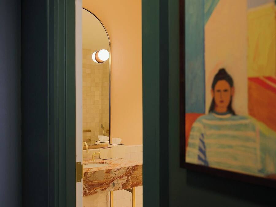 Une salle de bain avec un lavabo en marbre, un miroir et un tableau encadré au mur.