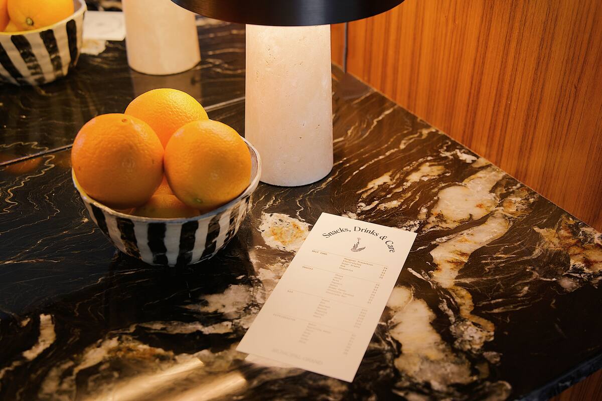 A marble countertop with a bowl of oranges and a menu.